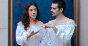 Un dona i un home vestits amb brusa blanca es donen la mà i es miren. La imatge és borrosa.