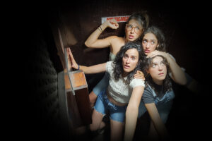 Un grup de quatre dones amb expressions de sorpresa en un espai estret.